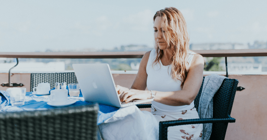 A woman working from a balcony: remote workers salaries