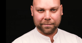 A portrait of Ned Dervenkov, CEO of BESCO wearing a white shirt on a black background