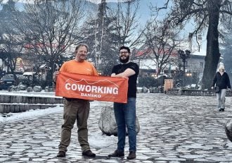 Two men holding an orange banner in Bansko, Bulgaria