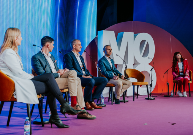 3 men and 2 women on stage in a panel
