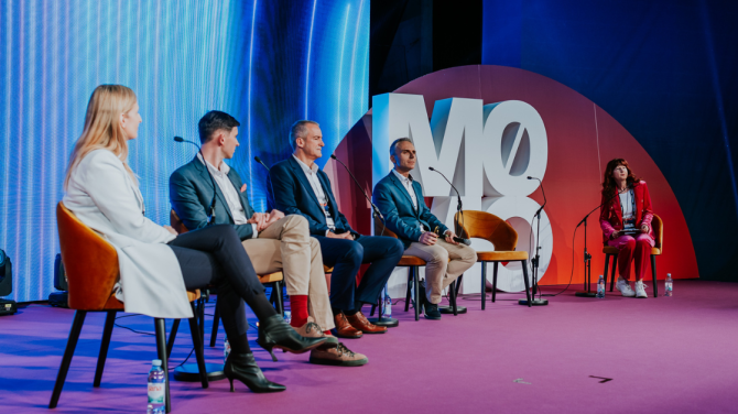 3 men and 2 women on stage in a panel