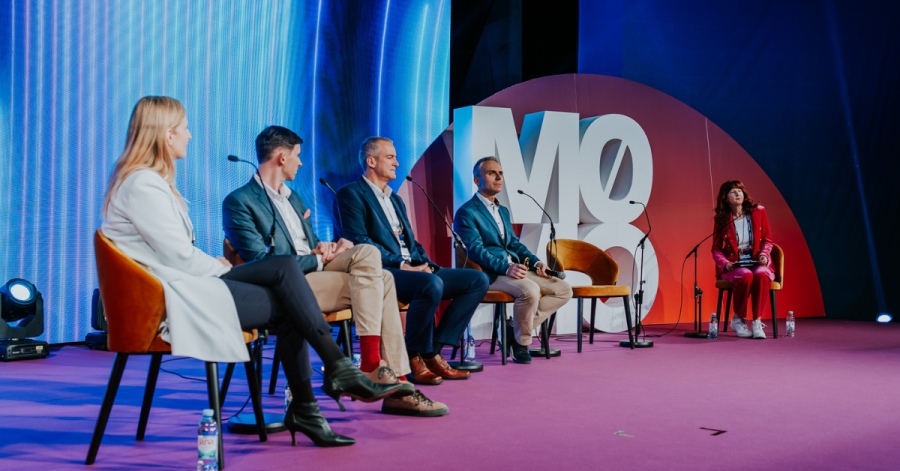 3 men and 2 women on stage in a panel