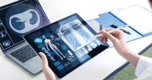 health tech doctor's hand holding tablet and monitoring patients health remotely with laptop in the background monitoring the patient